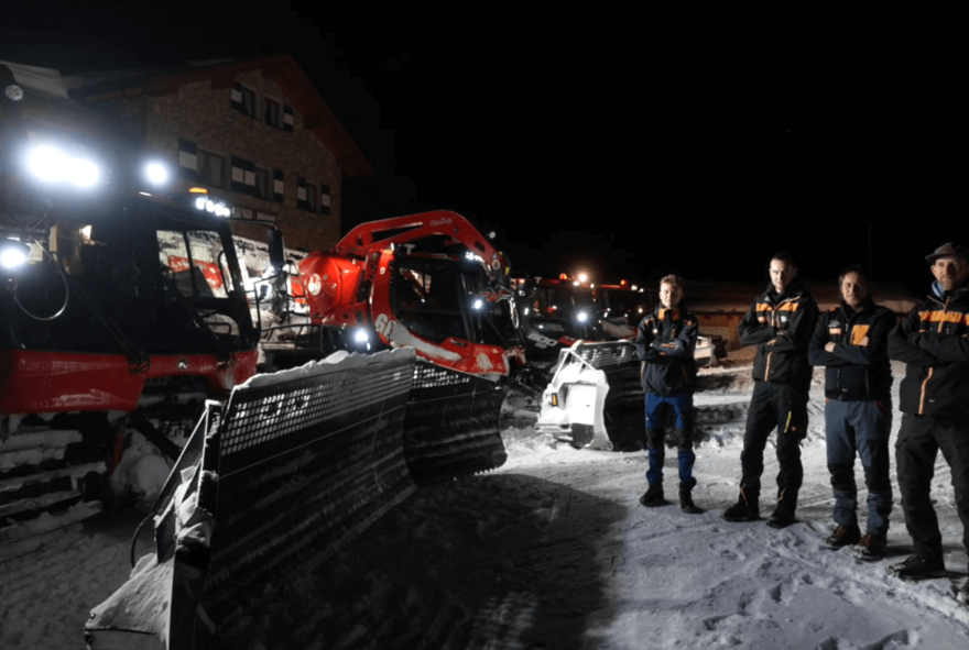 pistenraupen-in-der-nacht-mit-team drei pistenraupen in der nacht am stubaier gletscher mit vier männern daneben